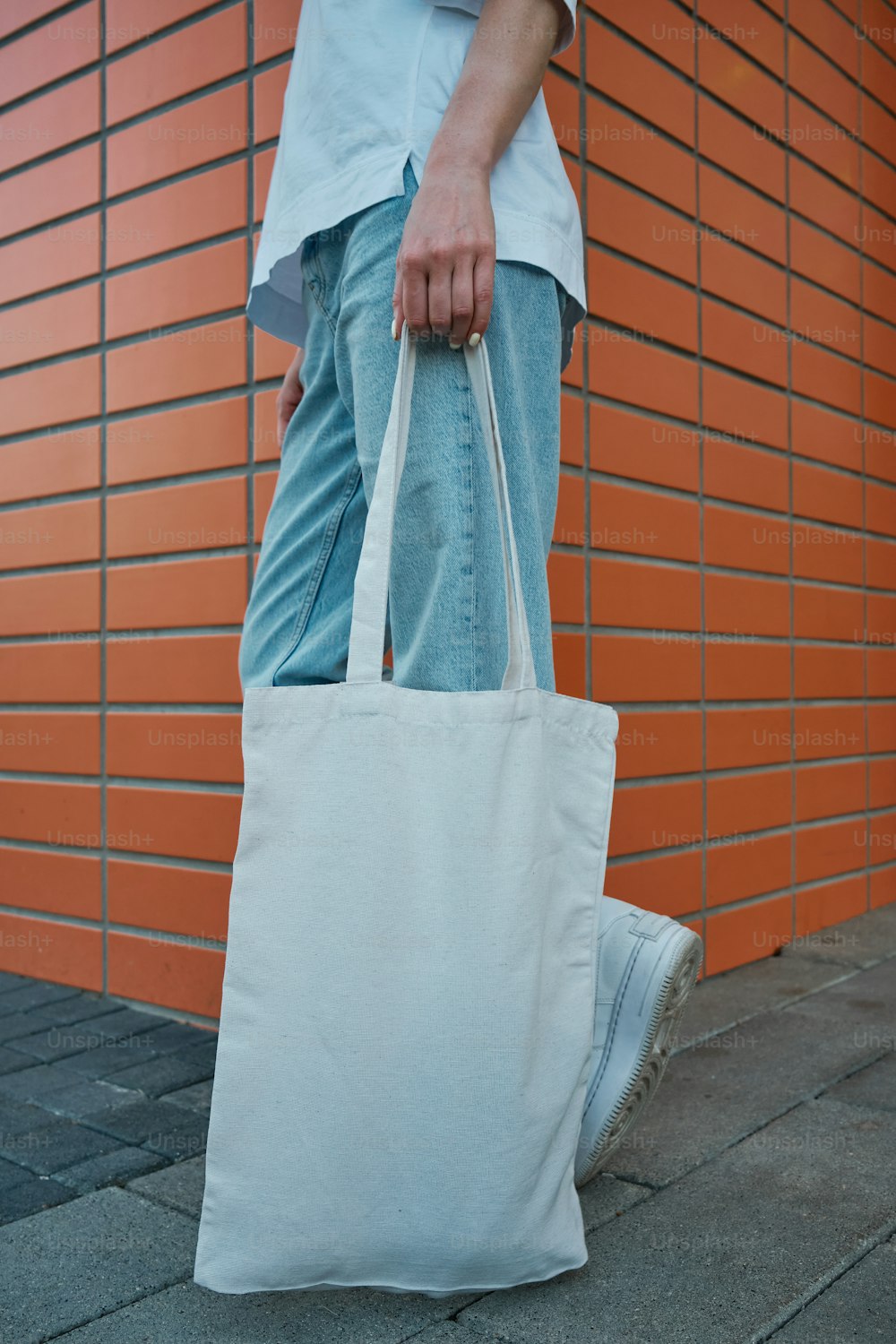 una persona che trasporta una borsa bianca su un marciapiede