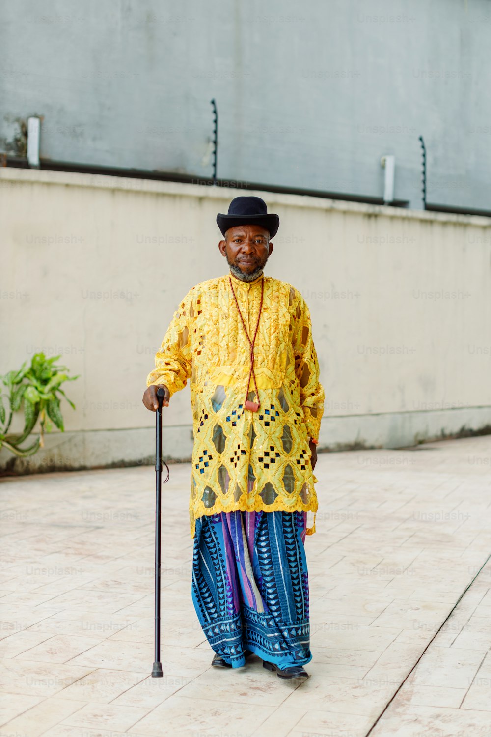 a man in a yellow shirt and blue pants holding a cane