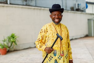 a man in a yellow shirt and black hat holding a cane