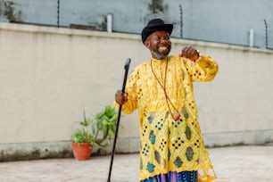 a man in a yellow shirt and hat holding a cane