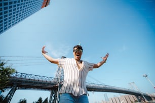 Un hombre parado frente a un puente con los brazos extendidos