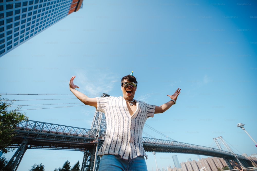 a man standing in front of a bridge with his arms outstretched