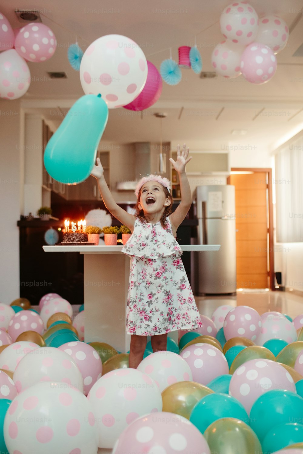 a little girl standing in a room filled with balloons
