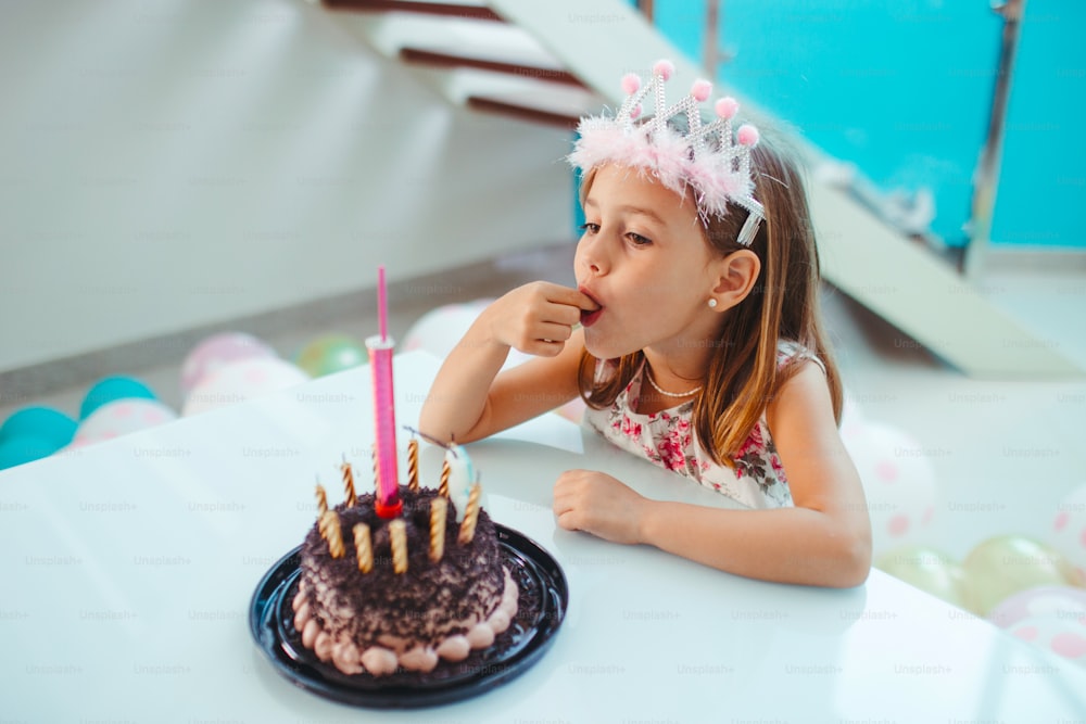 a little girl blowing out candles on a birthday cake
