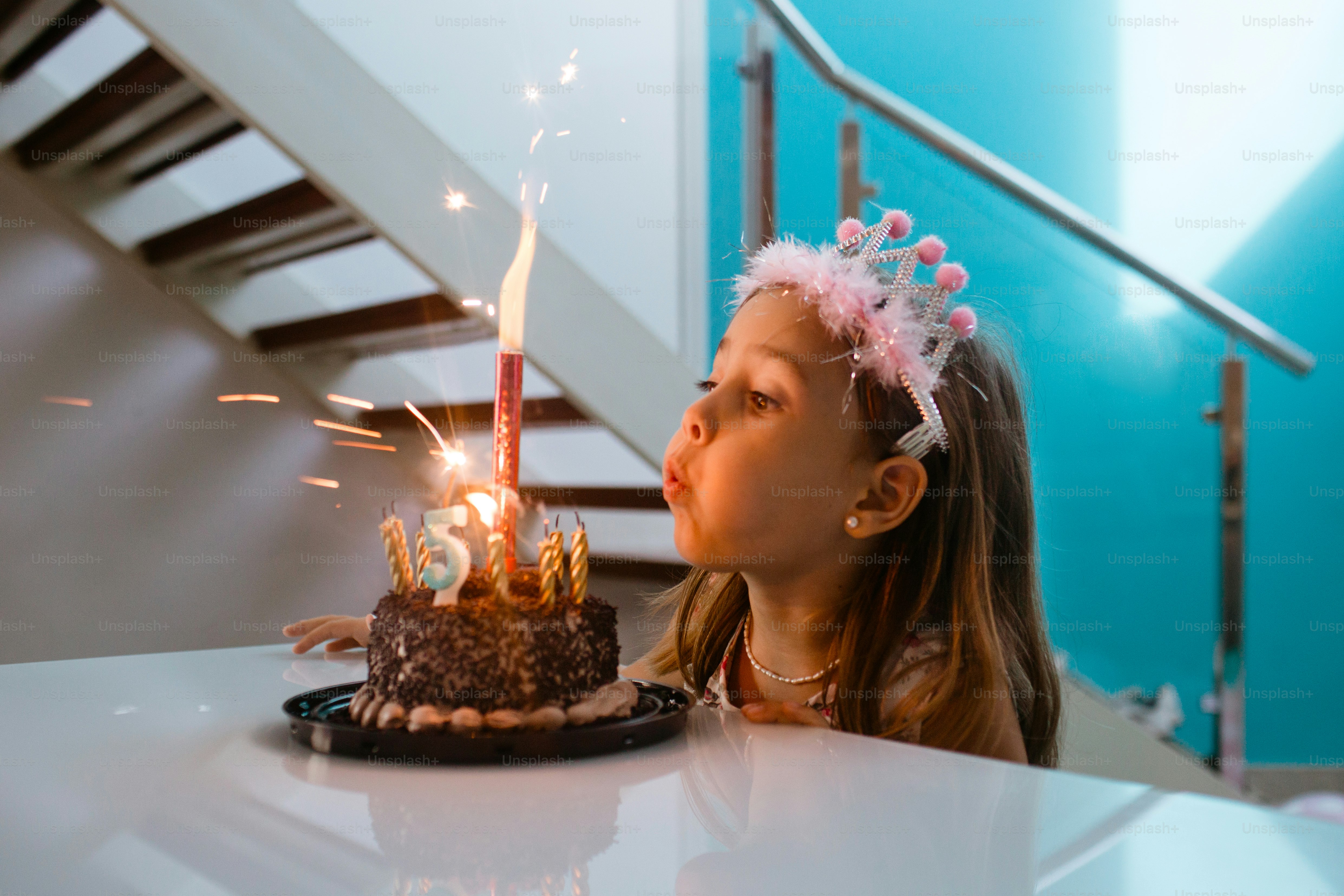a little girl blowing out candles on a cake