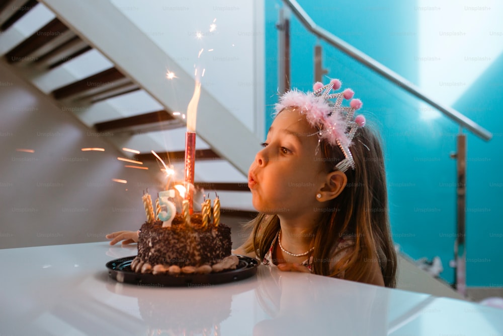 a little girl blowing out candles on a cake