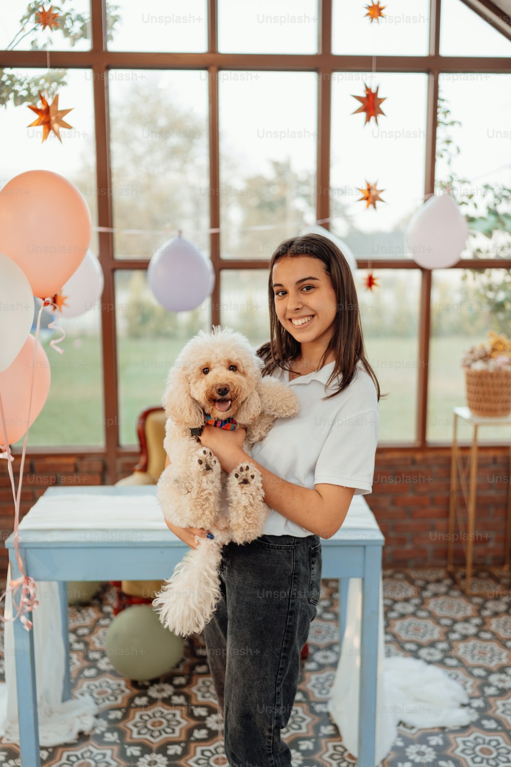 a woman holding a dog in front of balloons