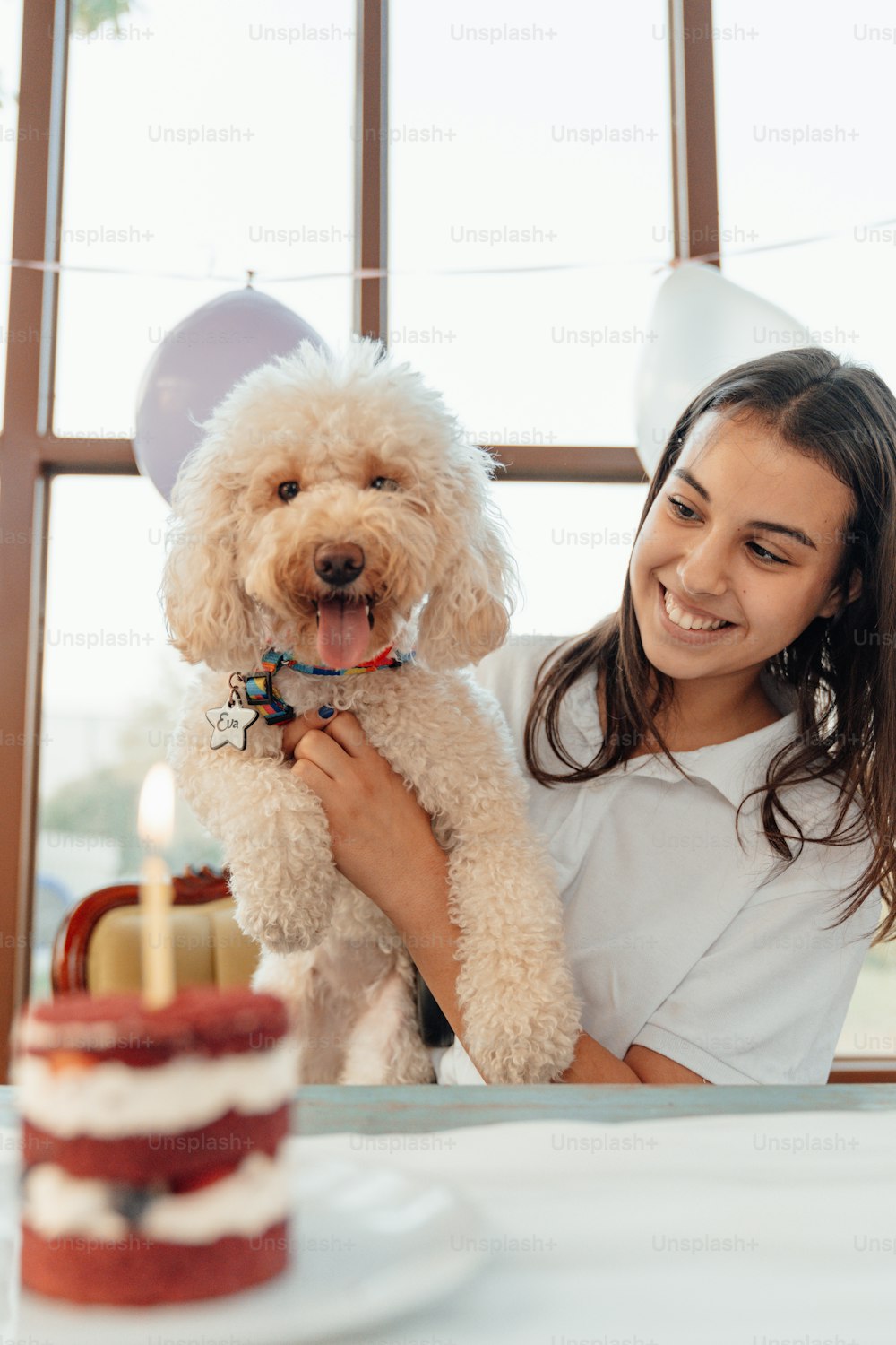 a girl holding a dog in front of a birthday cake