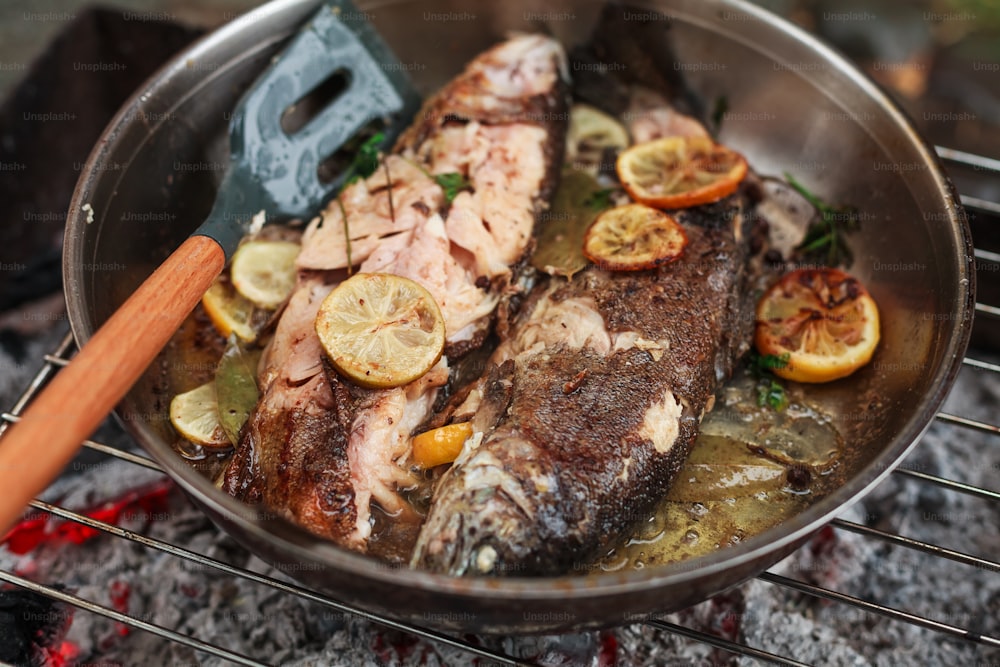 a pan filled with fish sitting on top of a grill