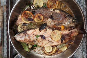 a pan filled with fish and lemons on top of a stove