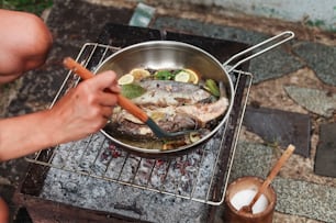 una persona sta cucinando pesce su una griglia