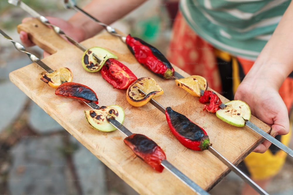 a person holding a wooden cutting board with different types of food on it