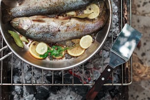 a fish is cooking on a grill with lemon slices