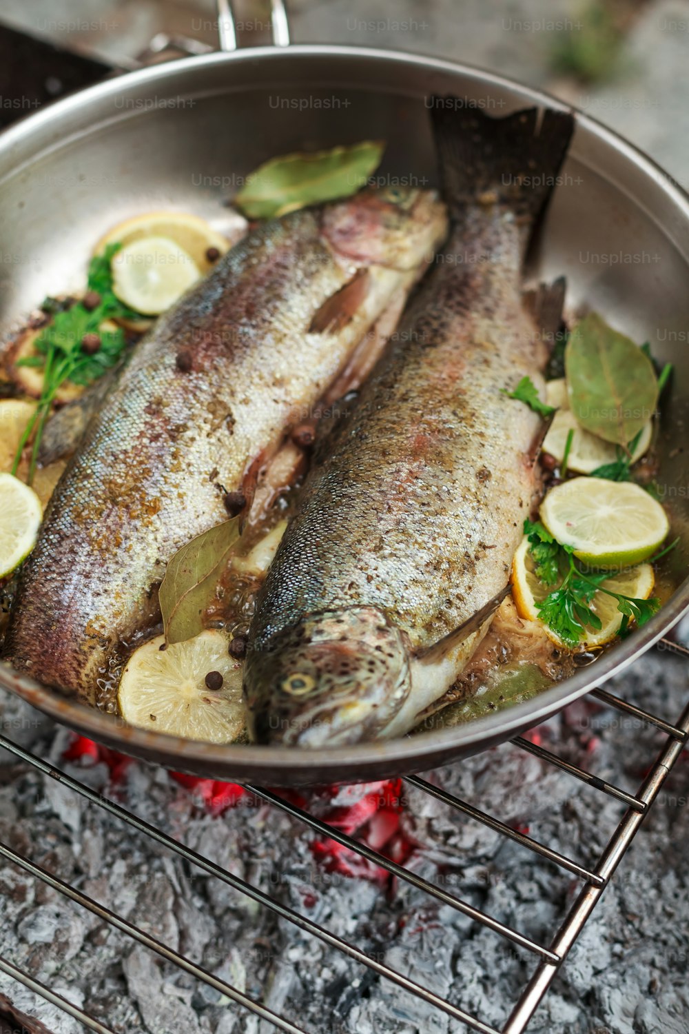 two fish are cooking in a pan on a grill