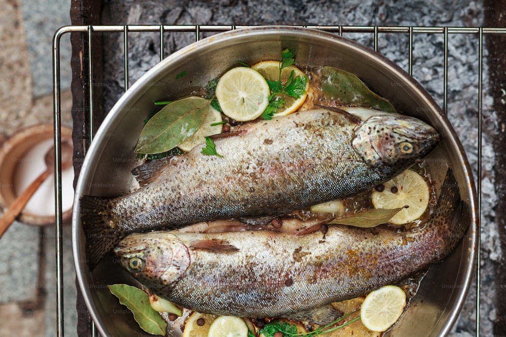 two fish in a pan with lemons and herbs