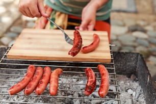 a person cooking hot dogs on a grill