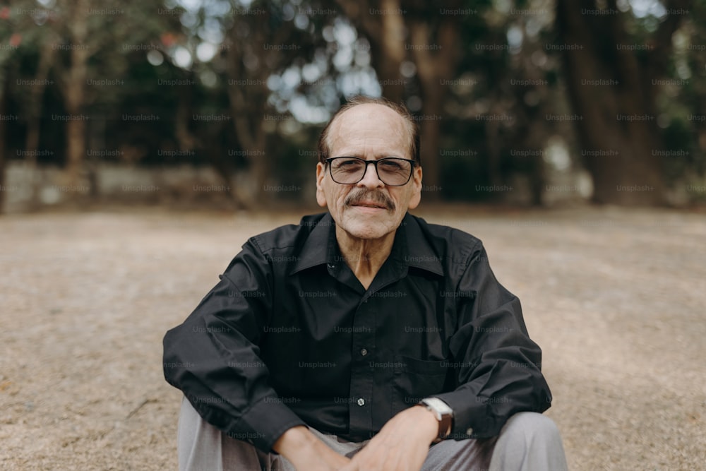a man sitting on the ground wearing glasses