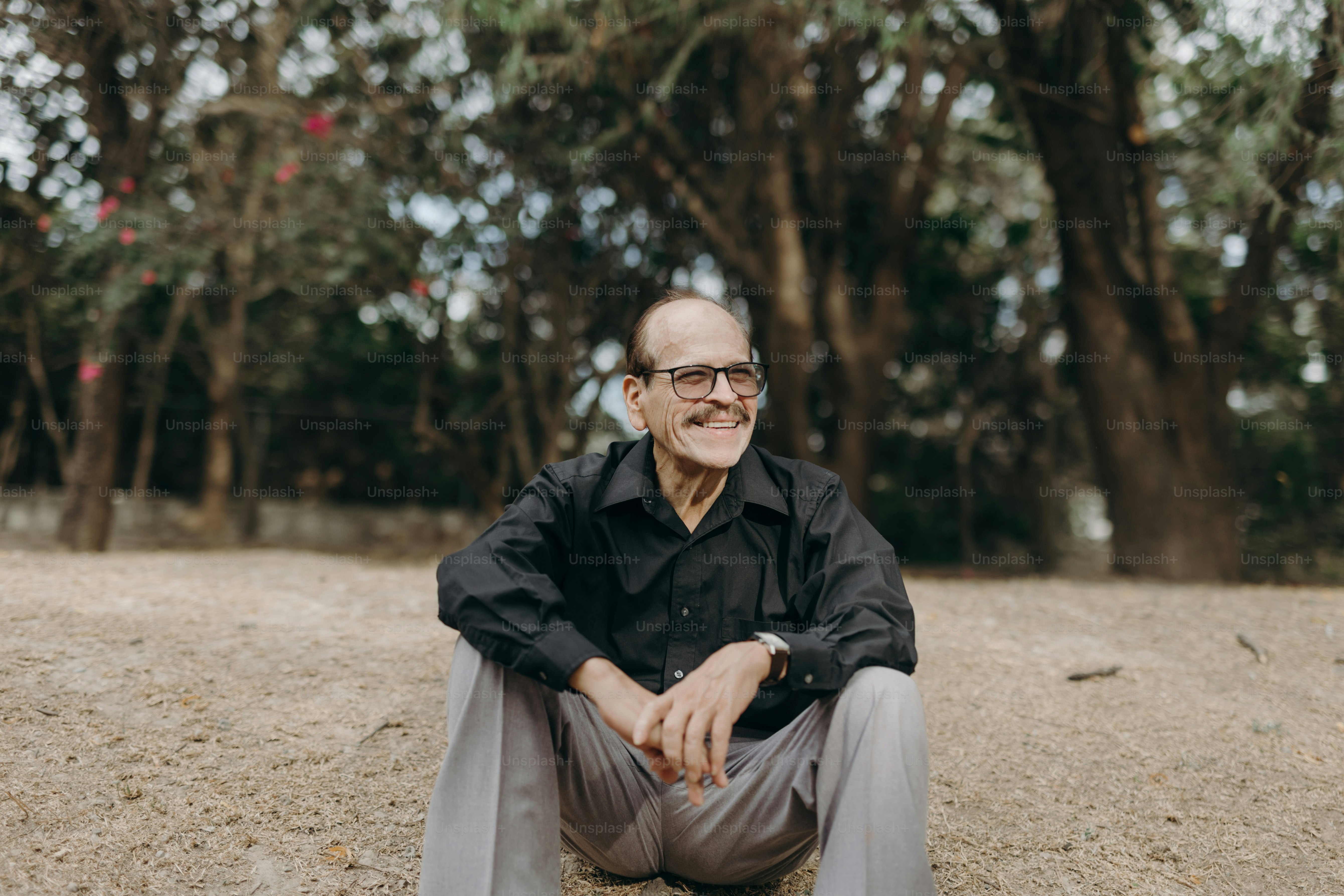 a man sitting on the ground in front of some trees