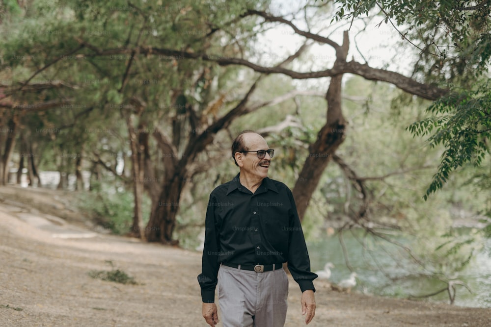 a man walking down a dirt road next to a forest