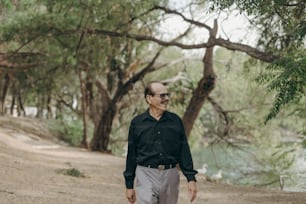 a man walking down a dirt road next to a forest
