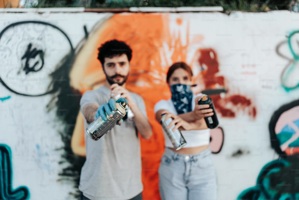a man and a woman taking a selfie in front of a wall with graffiti