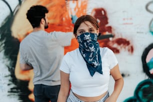 Un hombre y una mujer parados frente a una pared cubierta de graffiti