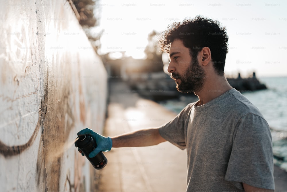 Un uomo sta dipingendo un muro vicino all'acqua