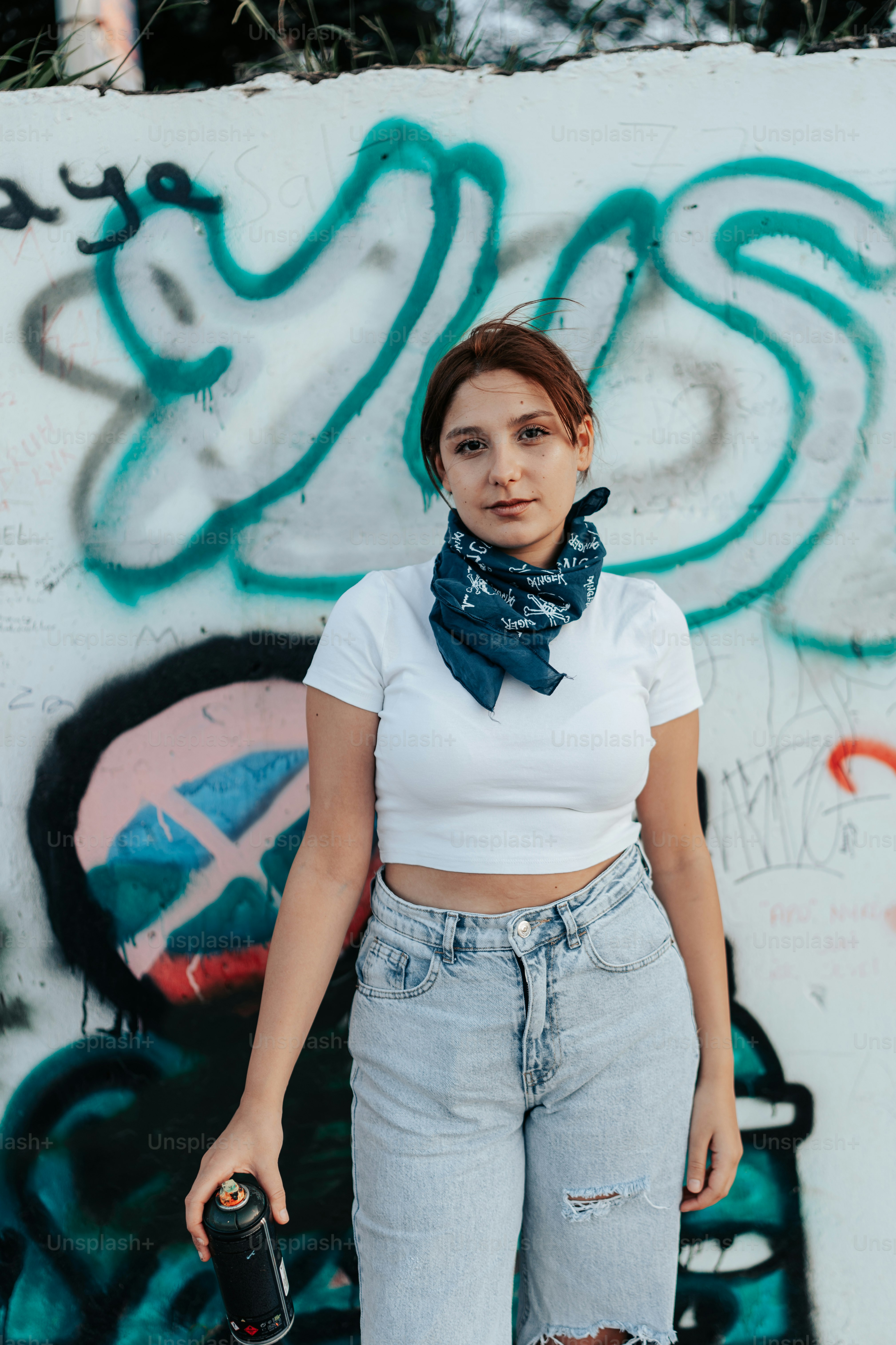 uma mulher em frente a um muro com pichações