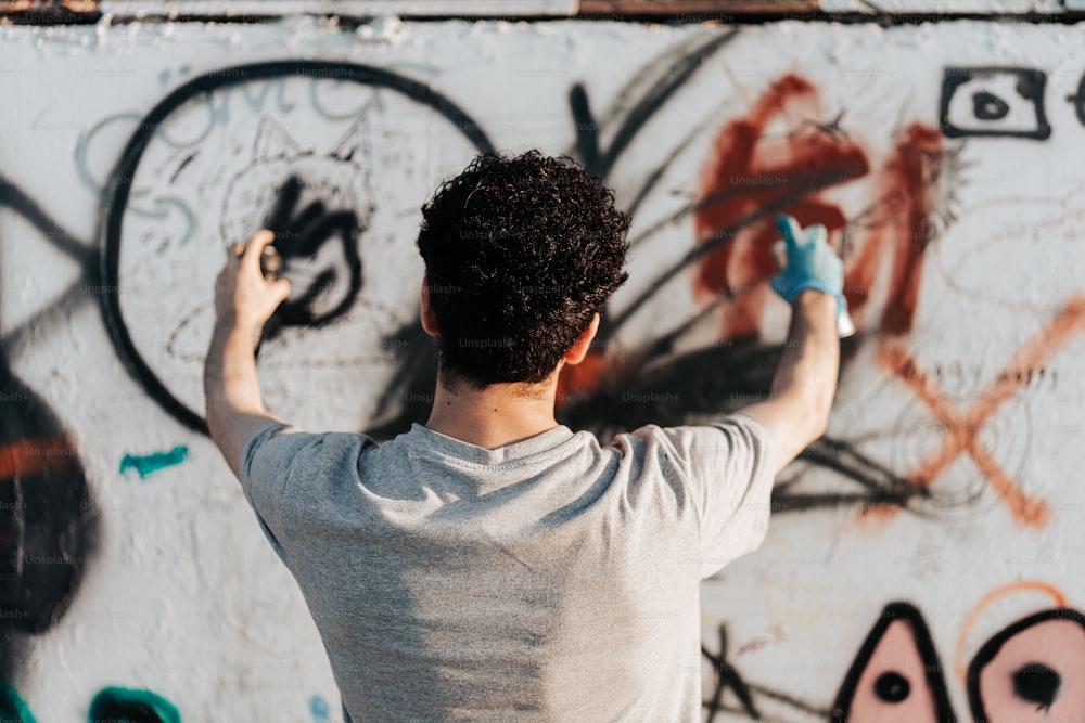 Un uomo spruzza che dipinge graffiti su un muro