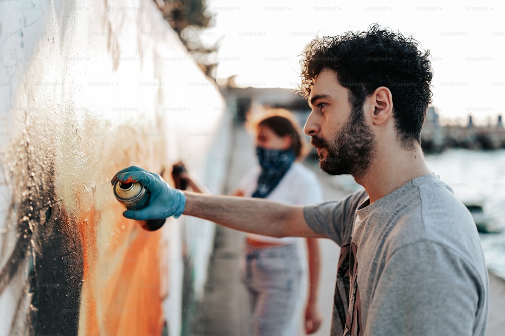 a man spray painting on a wall with blue gloves