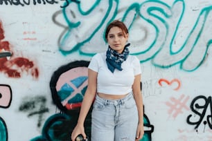 a woman standing in front of a wall covered in graffiti