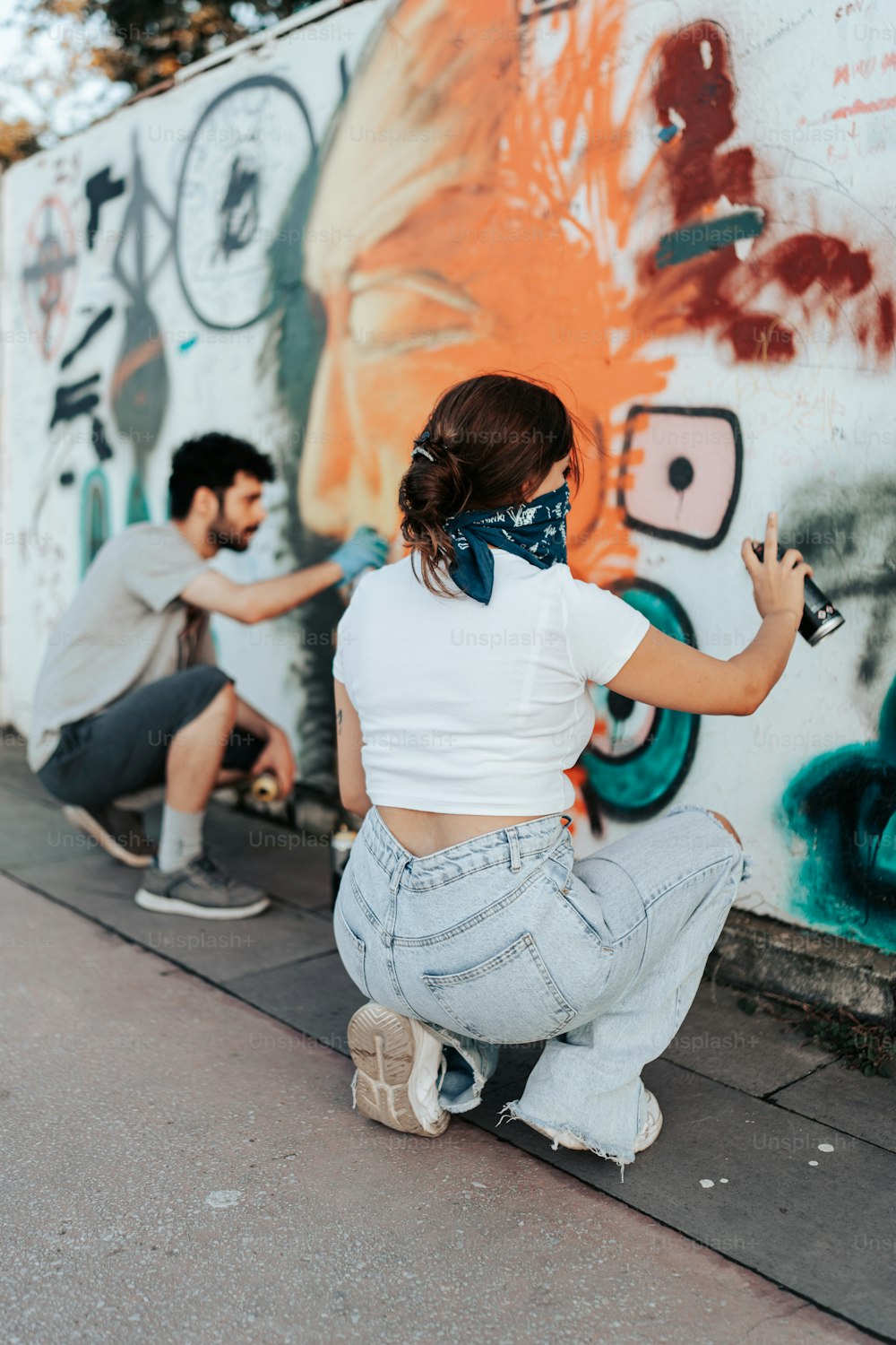 a man and a woman painting a wall with graffiti