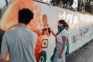 a woman is painting a wall with graffiti