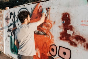 a man painting a wall with graffiti on it