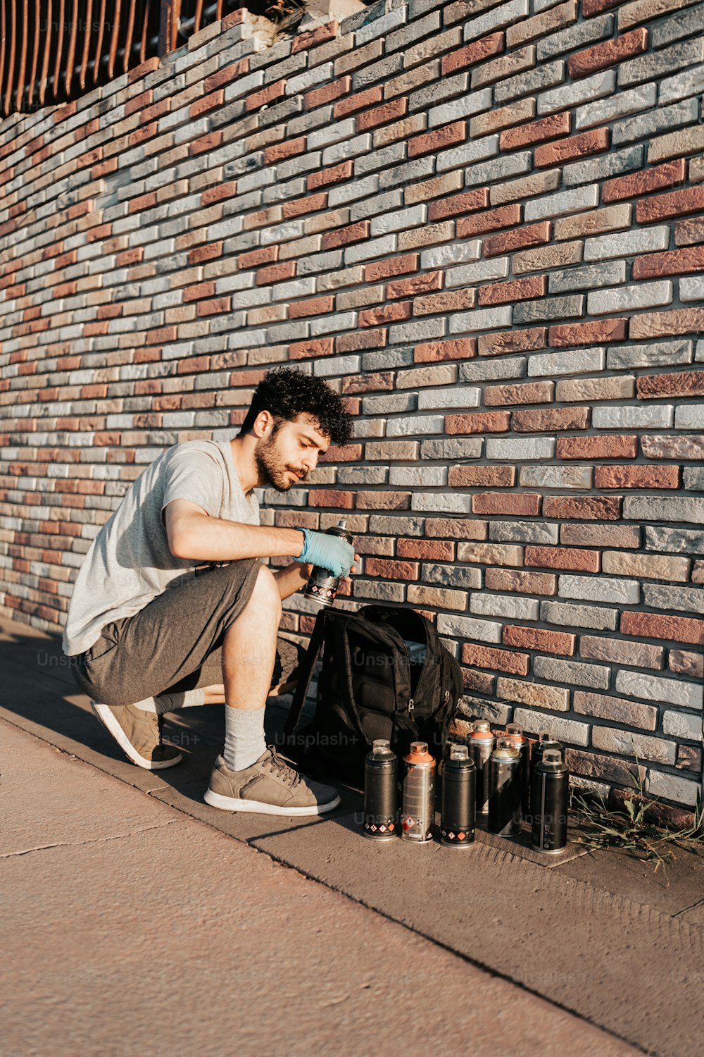 a man sitting on the side of a brick wall