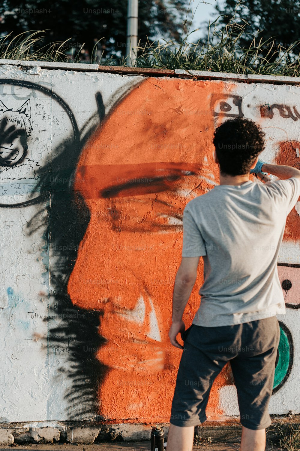 a man painting a wall with orange spray paint