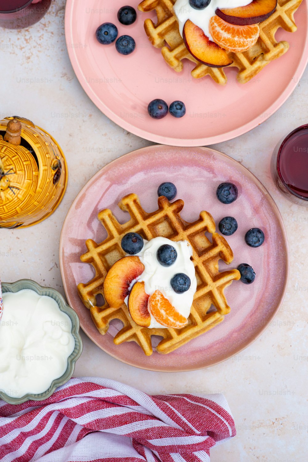two pink plates topped with waffles covered in fruit