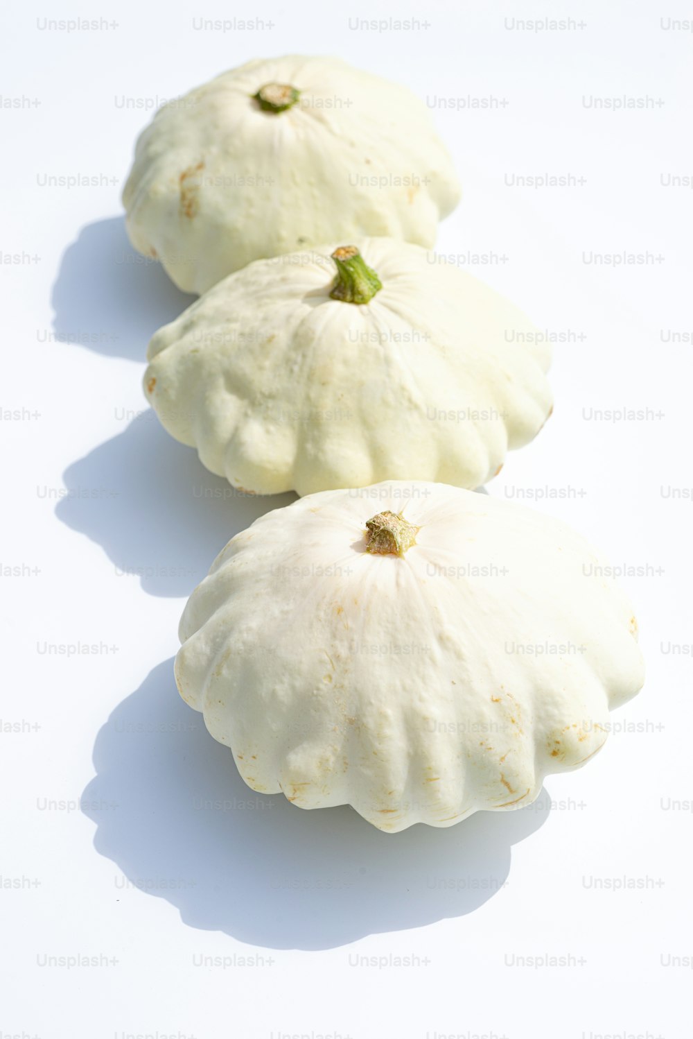three white gourds sitting on a white surface