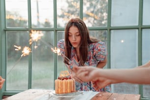 a woman blowing out sparklers on a cake