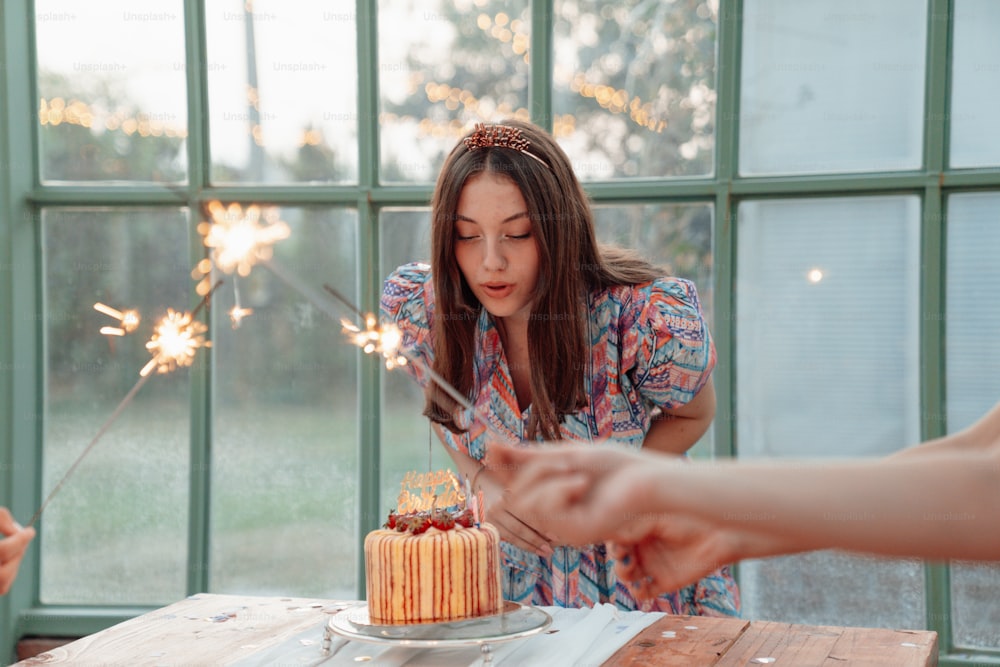 a woman blowing out sparklers on a cake