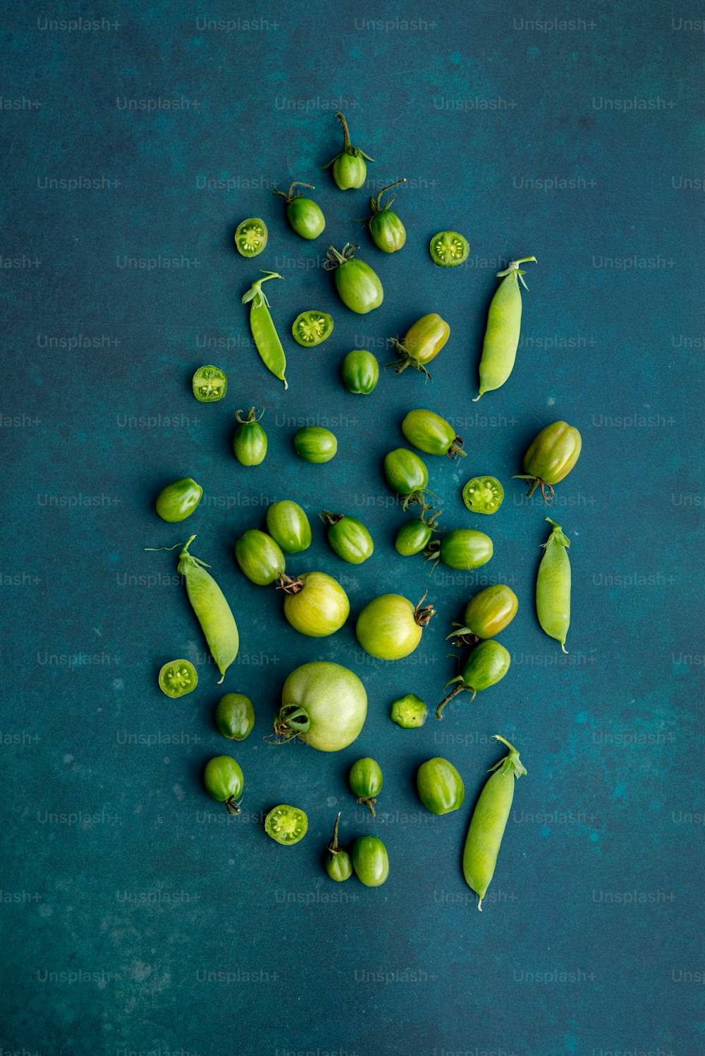 a group of green fruits and vegetables on a blue surface