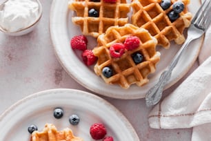 a plate of waffles with berries and whipped cream