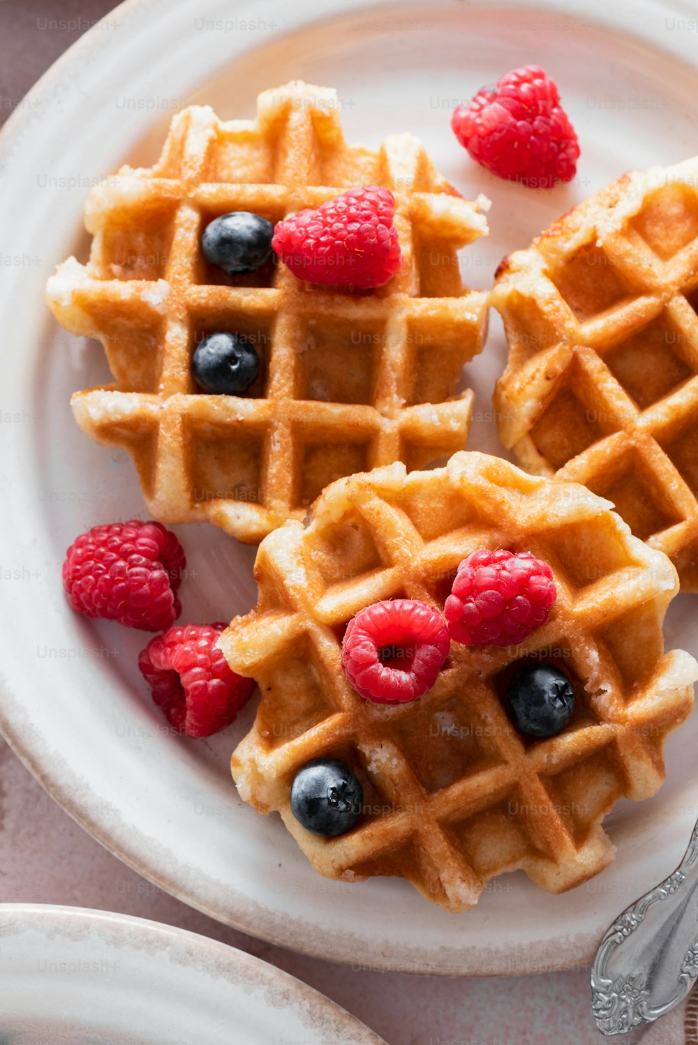 a plate of waffles with raspberries and blueberries