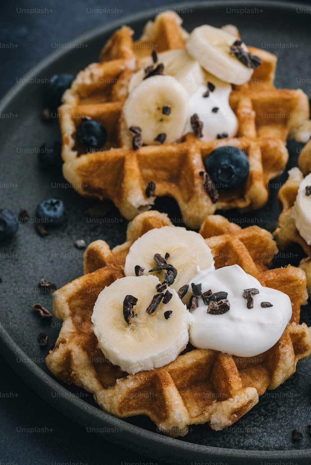 a plate of waffles topped with bananas and blueberries
