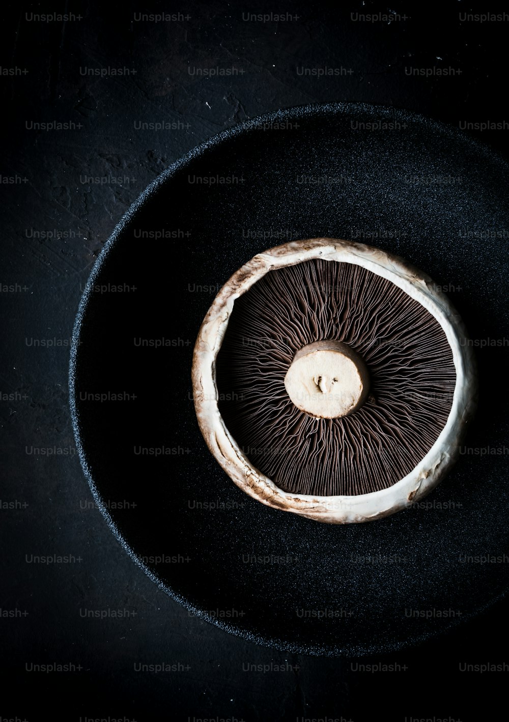 une assiette noire avec un champignon à l’intérieur
