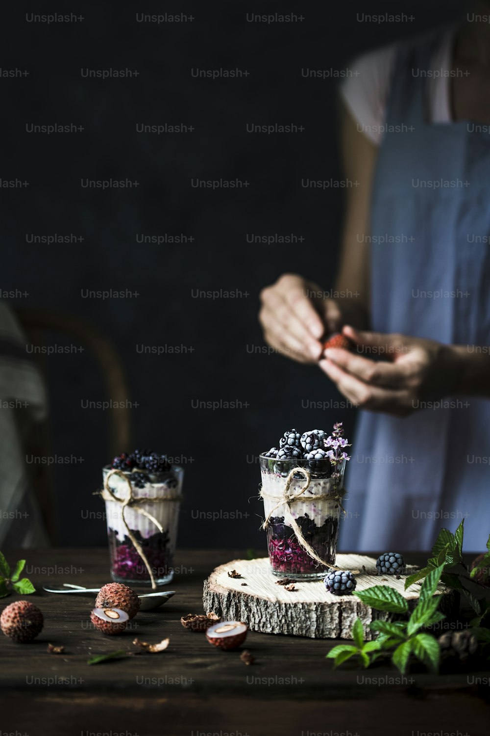 a woman standing next to a wooden table with two desserts on it