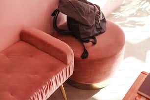 a backpack sitting on top of a pink ottoman