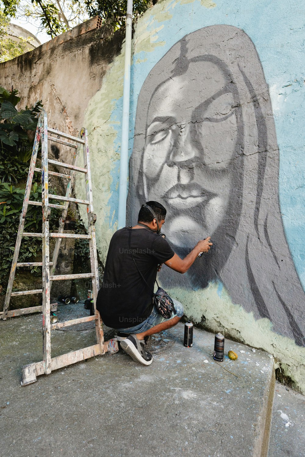 Ein Mann malt ein Wandbild an der Seite eines Gebäudes