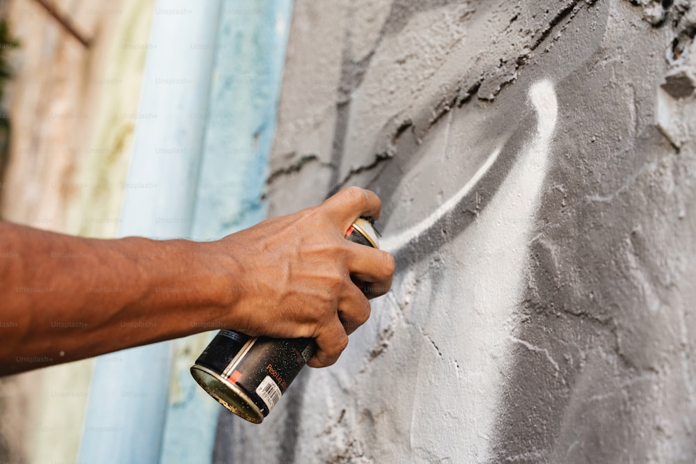 a person spray painting a wall with a paint roller