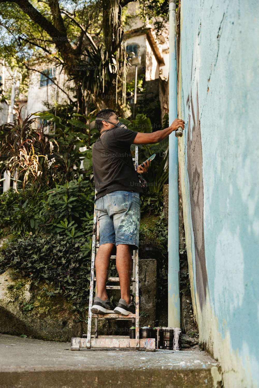 Un hombre en una escalera pintando el costado de un edificio